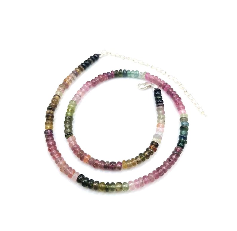 May include: A multi-colored gemstone necklace with a silver chain. The necklace is made of small, round beads in shades of pink, green, blue, and black.