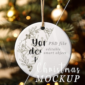 May include: White ceramic Christmas ornament with a snowflake and floral design. The ornament is hanging from a brown string and has the text "your design here" on it. PSD file, editable smart object. Christmas mockup.