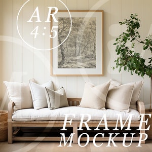 May include: A framed black and white print of a forest scene hangs above a white cushioned bench with beige pillows. A potted green plant stands to the right of the bench. The bench is made of wood and has a woven basket on each end.