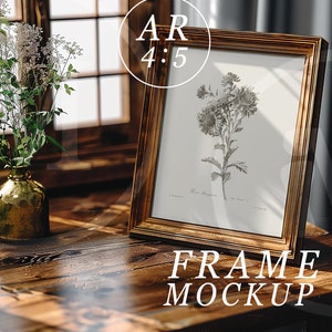 K&ouml;nnte beinhalten: Ein goldfarbener Bilderrahmen mit einem Schwarzwei&szlig;-Botanischen Druck einer Blume. Der Rahmen steht auf einem Holztisch mit einer Vase mit wei&szlig;en Blumen im Hintergrund.