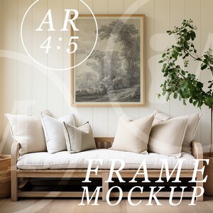 May include: A white couch with beige pillows sits in a room with white walls and wood floors. A framed black and white print hangs on the wall above the couch. A potted plant with green leaves stands to the right of the couch. The text "FRAME MOCKUP" is printed on the floor in front of the couch.
