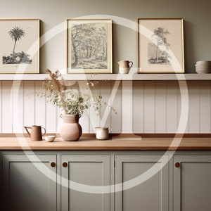 K&ouml;nnte beinhalten: K&uuml;cheninterieur mit gerahmten botanischen Drucken, einer Vase mit Trockenblumen und verschiedenen Keramikkr&uuml;gen und -schalen. Die Schr&auml;nke sind in einem ged&auml;mpften Gr&uuml;n gehalten, mit Holz-Arbeitsplatten und goldenen Beschl&auml;gen.