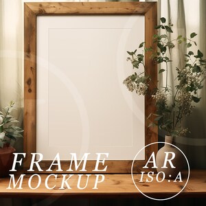 May include: A wooden picture frame mockup with a white mat, set on a wooden table. The frame is surrounded by a small potted plant and a vase of flowers. The text "FRAME MOCKUP" and "AR ISO:A" are visible.