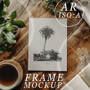 May include: A black and white illustration of a palm tree on a white background, framed and sitting on a wooden table with a cup of coffee and plants. The text "FRAME MOCKUP" is below the frame.