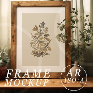 May include: A framed botanical print featuring a collection of dried flowers in shades of yellow, blue, and brown. The artwork is displayed in a rustic, light brown wooden frame. The words "FRAME MOCKUP" are at the bottom of the frame.