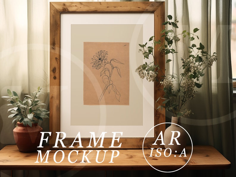 May include: A framed sunflower sketch in a rustic wooden frame. The artwork is on a tan background with a white mat. The words "FRAME MOCKUP" are at the bottom of the frame. A small plant in a terracotta pot and a vase of flowers are on the wooden table.