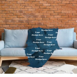 Może przedstawiać: Ciemnoniebieski koc z marmurkowym wzorem i złotymi plamkami jest narzucony na jasnoniebieską sofę. Na kocu widnieją białe napisy "Design here" i "Your". W tle ceglana ściana.