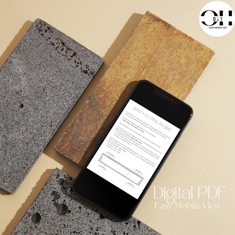 Peut inclure: Un smartphone noir affichant un guide PDF num&eacute;rique intitul&eacute; STEP 4: CUTTING TO SIZE, avec des instructions textuelles et un sch&eacute;ma technique d'une planche rectangulaire, pos&eacute; sur trois dalles de pierre rectangulaires aux textures grises et brunes.