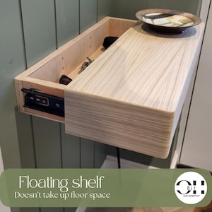 Peut inclure: Une &eacute;tag&egrave;re flottante en bois clair avec un tiroir coulissant int&eacute;gr&eacute;, fix&eacute;e au mur. Le tiroir est entrouvert, r&eacute;v&eacute;lant son contenu. Un bol d&eacute;coratif peu profond, rond et multicolore est pos&eacute; sur la surface sup&eacute;rieure de l'&eacute;tag&egrave;re.