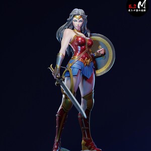 May include: A Wonder Woman statue in a dynamic pose, holding a sword and shield. The figure wears a red and blue costume with gold accents, boots, and a tiara. The statue is on a detailed base, with the "esmmonster" logo visible.