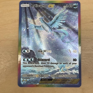 Może przedstawiać: Karta Pokémon Articuno ex z niebiesko-białą ilustracją Articuno. Karta ma holograficzne wykończenie i zawiera tekst "Ice Wing" i "Blizzard".