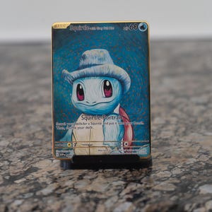 May include: A gold-bordered Squirtle-Portrait Pokémon card. The card features a blue Squirtle wearing a gray hat. The card text reads "Search your deck for a Squirtle and put it onto your Bench. Then, shuffle your deck."
