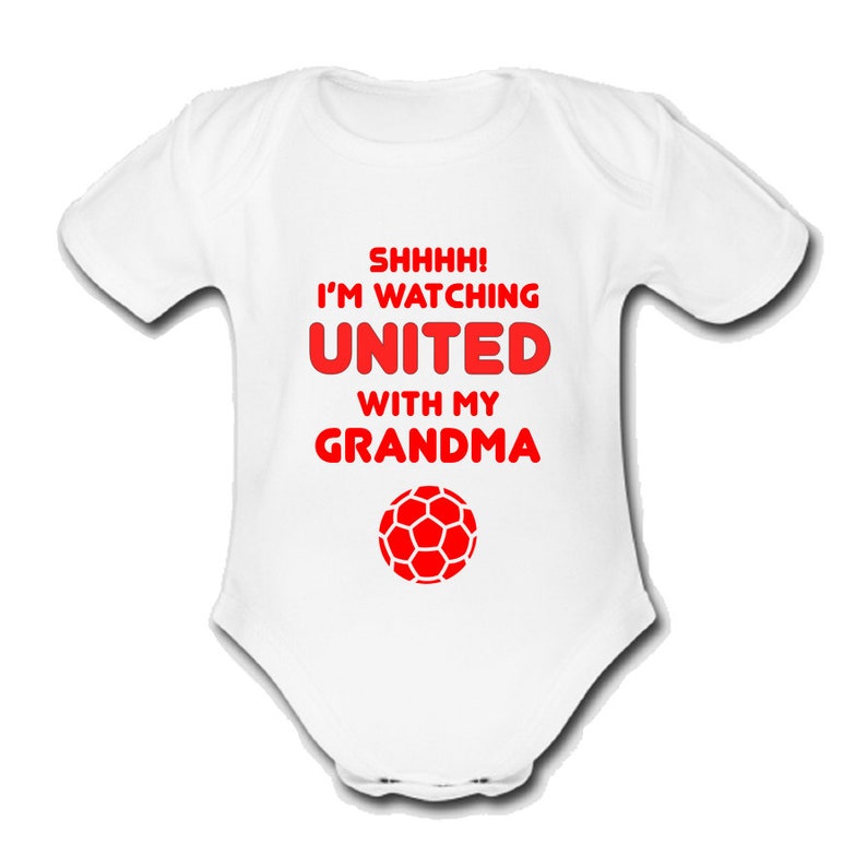 May include: White baby grow with red text that reads "SHHHH! I'M WATCHING UNITED WITH MY GRANDMA" and a red football graphic.
