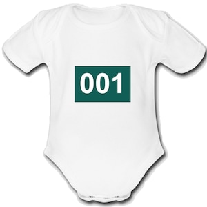 Peut inclure: Combinaison bébé blanche avec un rectangle vert sur le devant qui dit "001" en blanc.