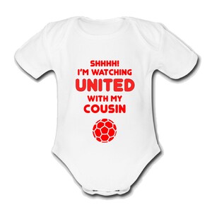 May include: White baby grow with red text that reads "Shhhh! I'm watching United with my cousin" and a red football graphic.