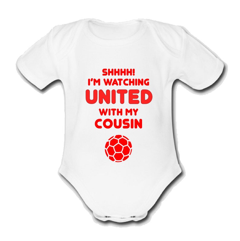 May include: White baby grow with red text that reads "Shhhh! I'm watching United with my cousin" and a red football graphic.