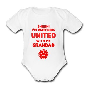 May include: White baby grow with red text that reads "Shhhh! I'm watching United with my Grandad" and a red football graphic.