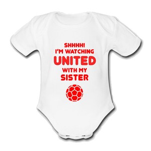 May include: White baby grow with red text that reads "Shhhh! I'm watching United with my sister" and a red football graphic.