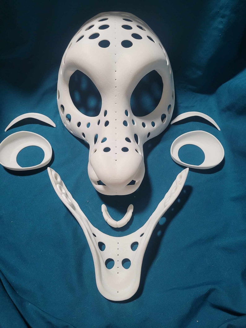 May include: White unfinished mask with multiple holes and a separate nose piece. The mask is made of a smooth, hard material and is ready to be painted.