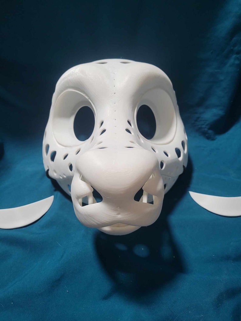 May include: White unfinished furry animal mask with holes for eyes and nose. The mask is made of a smooth, hard plastic and is ready to be painted.