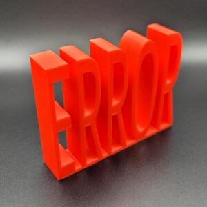 May include: A red 3D printed word "ERROR" with each letter standing on its own. The letters are all the same size and are made of a smooth, glossy plastic.