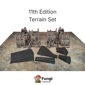 Può includere: Un set di terreno da tavolo con il testo "11th Edition Terrain Set". Il set include edifici in miniatura in rovina e vari pezzi di terreno neri con testo verde. Lo sfondo è una superficie strutturata simile a un deserto.