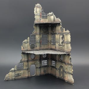 Könnte beinhalten: Ein detailliertes Modell eines zerstörten Gebäudes mit mehreren Ebenen und Fenstern. Das Gebäude besteht aus grauen und braunen Materialien und hat einen verwitterten Look. Das Modell ist perfekt für Tabletop-Spiele oder als Dekorationsstück.