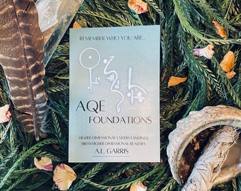 May include: A book titled "AQE Foundations" with the subtitle "Higher Dimensional Understandings Birth Higher Dimensional Realities" by A.L. Garris. The cover features a blue and white symbol with the words "Remember Who You Are..." at the top.