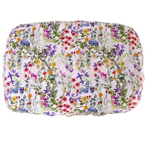 May include: A rectangular pillow with a vibrant floral pattern. The design features a white background covered in colorful flowers, including red, purple, yellow, and blue blooms, with green foliage. The pillow has a soft, rounded shape.