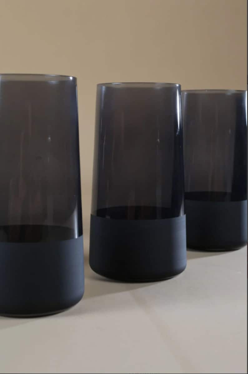 May include: Three dark gray glass tumblers with a black painted bottom.