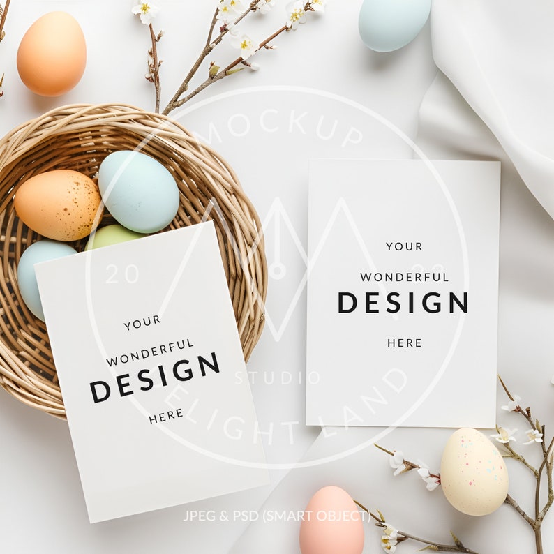 May include: Two blank white cards with the text "YOUR WONDERFUL DESIGN HERE" on each card. The cards are laying on a white surface with a wicker basket filled with pastel colored Easter eggs and a sprig of white blossoms.