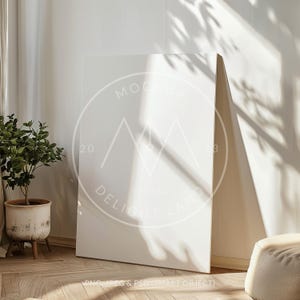 Puede incluir: Una maqueta de lienzo blanco con una sombra de una ventana y plantas. El lienzo está apoyado contra una pared blanca. El texto "MOCKUP 2023 DELIGHT LAND" está impreso en el lienzo. PNG, JPEG & PSD (SMART OBJECT).
