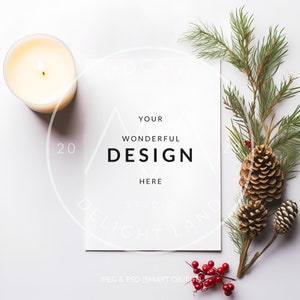 May include: A white card with the text "YOUR WONDERFUL DESIGN HERE" on a white background with a lit candle, pine branches, pine cones, and red berries.