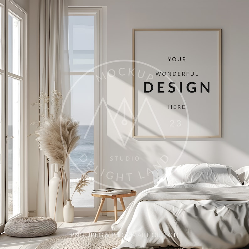 May include: A white bedroom with a large window overlooking the ocean. The bed is made with white linens and a throw pillow. A wooden side table with a book and a vase of dried flowers sits next to the bed. A framed poster with the text "YOUR WONDERFUL DESIGN HERE 23" hangs on the wall.
