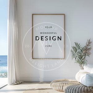 May include: A gold framed poster mockup with the text "Your Wonderful Design Here" in a circle with the text "Studio Delight Land" below it. The poster is hanging on a white wall in a room with a white couch, a potted plant, and a woven rug.