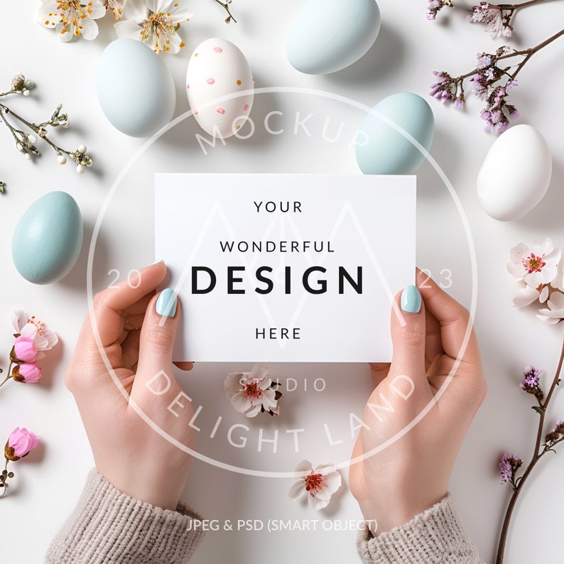 May include: A white card with the text "YOUR WONDERFUL DESIGN HERE" held by hands against a white background with blue and white Easter eggs, pink and white flowers, and green branches.