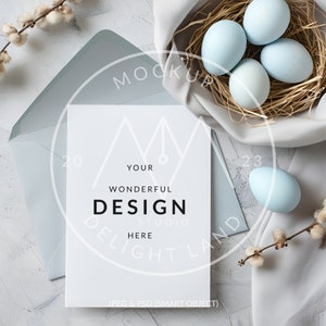 May include: A white card with the text "YOUR WONDERFUL DESIGN STUDIO HERE" in black text. The card is sitting on a white surface with a blue envelope and a nest of blue eggs.