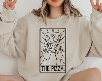 May include: A beige sweatshirt with a black and white illustration of a pizza slice tarot card. The card reads "The Pizza." and "XII."