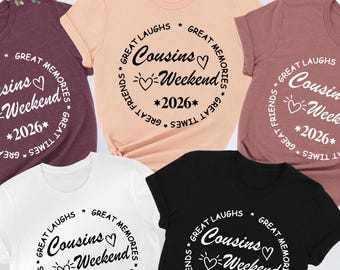 Könnte beinhalten: Verschiedene T-Shirts in Farben wie Weinrot, Pfirsich, Weiß und Schwarz. Jedes Shirt hat ein rundes Design mit dem Text "Cousins Weekend 2026". Eine blaue Jeans und eine braune Handtasche sind ebenfalls zu sehen.