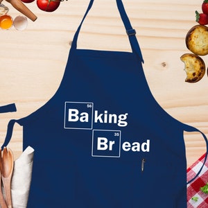 May include: A blue apron with the text "Baking Bread" in white letters. The text is styled to look like a periodic table element with the chemical symbols "Ba" and "Br".