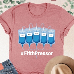May include: Heather mauve t-shirt with a graphic of five IV bags labeled "LEVO", "NEO", "VASO", "EPI", and "JC" and the text "#FifthPressor".