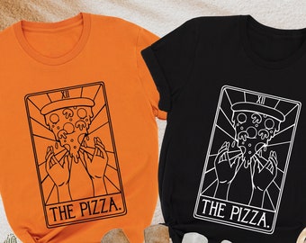 May include: Two t-shirts with a tarot card design featuring a pizza slice. The orange shirt has black text and the black shirt has white text. Both shirts say "The Pizza."