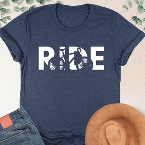 a t - shirt that says ride next to a hat and jeans