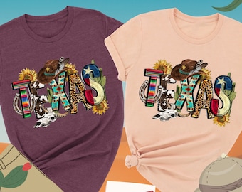 May include: Two t-shirts with the word "TEXAS" in colorful letters, featuring a cowboy hat, horseshoe, sunflowers, and a Texas flag. The shirts are available in heather maroon and heather peach.