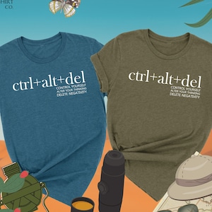 May include: Two t-shirts with the text "ctrl+alt+del" and the words "Control yourself, alter your thinking, delete negativity" printed on them. The t-shirts are in heather deep teal and heather olive colors.