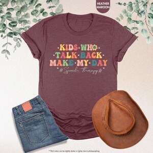 May include: Heather maroon t-shirt with the text "KIDS WHO TALK BACK MAKE MY DAY #Speech Therapy#" in rainbow colors.