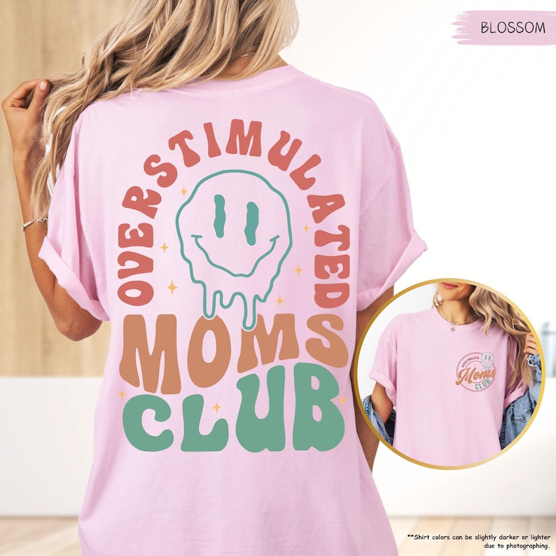 K&ouml;nnte beinhalten: Hellrosa T-Shirt mit dem Schriftzug "OVERSTIMULATED MOMS CLUB" in Retro-Schrift. Das Design zeigt ein schmelzendes Smiley-Gesicht. Das Shirt hat kurze &Auml;rmel und einen Rundhalsausschnitt.