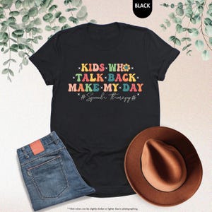 May include: Black t-shirt with a colorful retro design that says "Kids who talk back make my day #Speech therapy#"