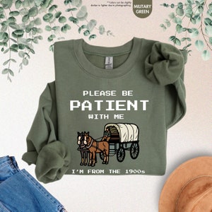 a green shirt with a horse drawn wagon on it