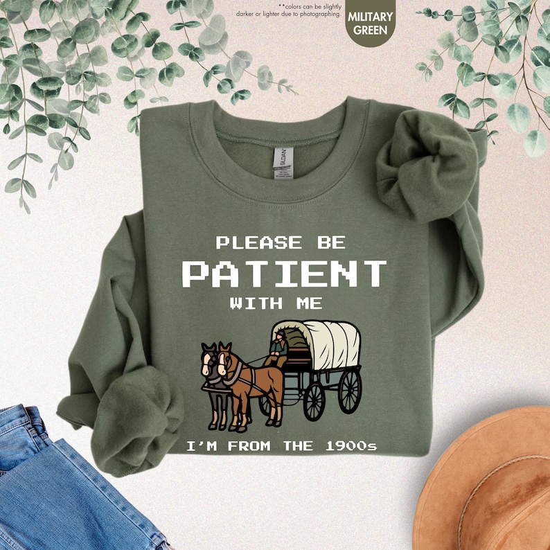 a green shirt with a horse drawn wagon on it